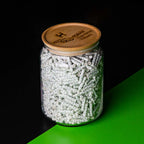 A clear jar with Hybrid Supreme Filters spilling out onto a green surface, with a wooden lid featuring the brand's logo.