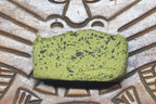 Green pollen with black specks on a textured surface with patterns