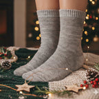 Person wearing gray hemp socks with a fireplace and Christmas decorations in the background